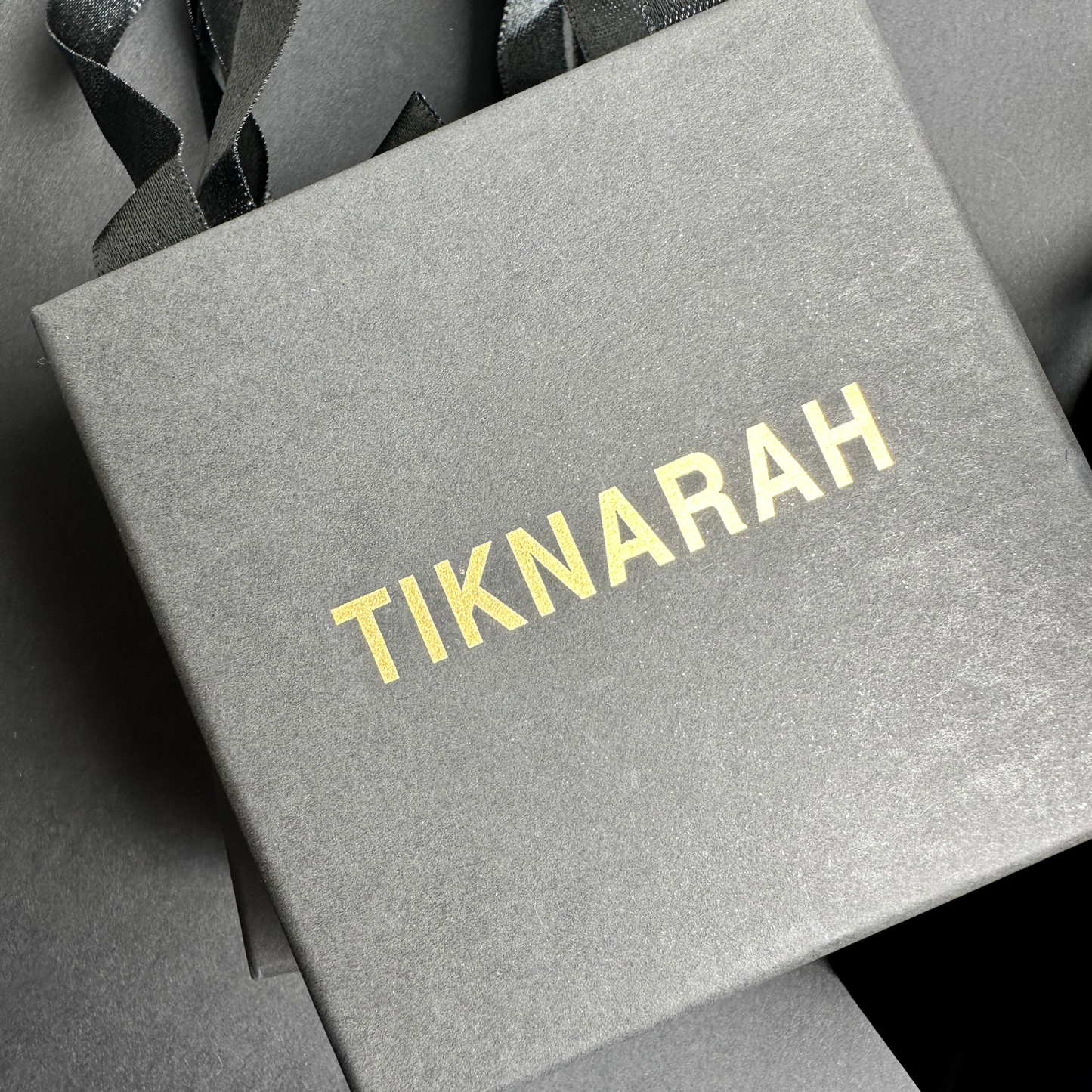 Gray box with 'TIKNARAH' branding on a dark background