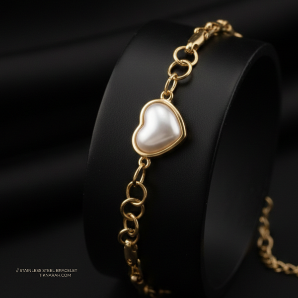 Gold bracelet with a heart-shaped pearl charm on a black background Heart pearl bracelet
Gold heart bracelet
Stainless steel jewelry for women
Tarnish-free gold bracelet
Heart charm link bracelet
Waterproof gold jewelry
Mother of pearl heart jewelry