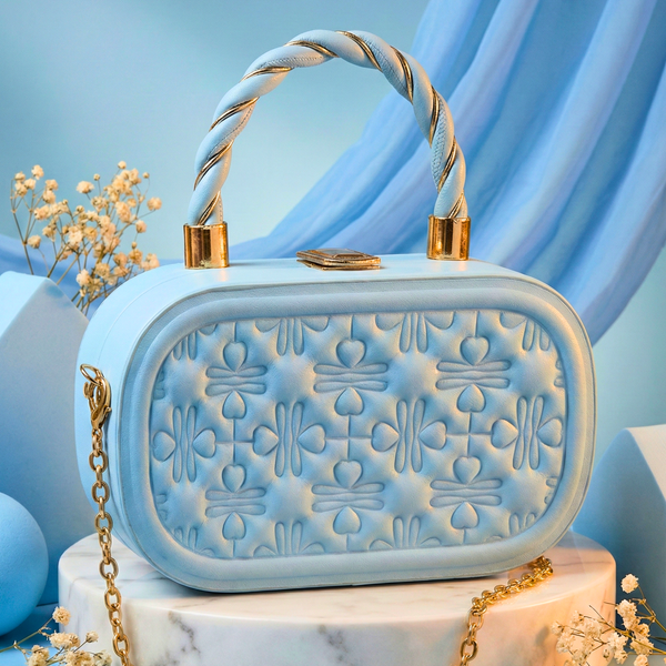 Light blue handbag with gold handle and chain on a marble stand with a blue curtain background Pastel blue handbag, box clutch, quilted evening bag, structured bag, gold top handle bag, powder blue purse, minaudière clutch, vintage style bag, wedding guest bag, detachable chain strap, geometric quilted pattern, baby blue accessory.