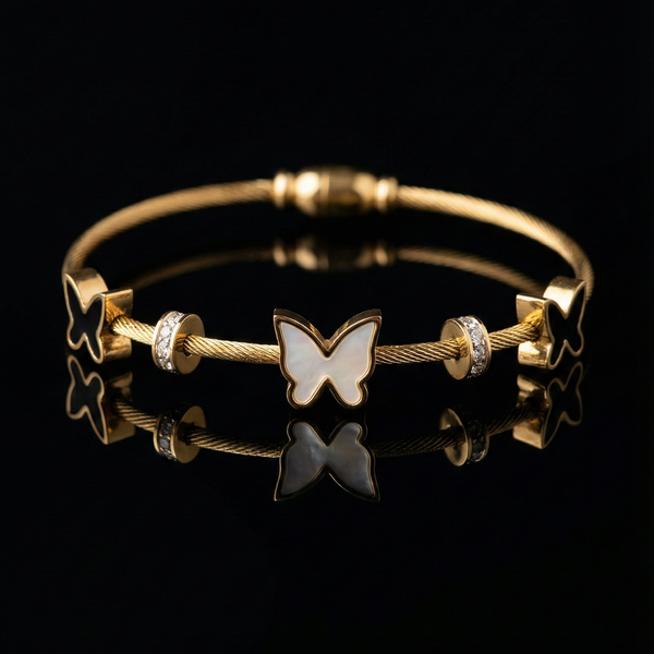 Gold bracelet with butterfly charm on a black background Gold butterfly bracelet, mother of pearl jewelry, black enamel butterfly charm, gold cable cuff, pave crystal bangle, luxury women's jewelry, twisted wire bracelet, magnetic clasp bangle, statement wristwear, gifts for her, elegant gold bangle, butterfly motif jewelry, two-tone butterfly bracelet.