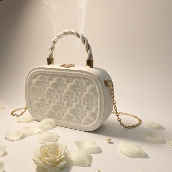 White textured handbag with gold accents on a light background with flowers and pearls. White quilted clutch, luxury evening bag, box handbag for women, bridal clutch bag, gold chain crossbody bag.