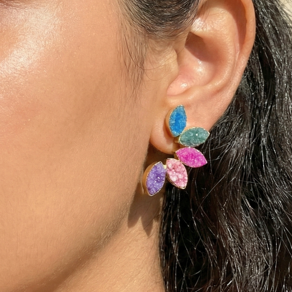 Close-up of an ear wearing colorful druzy earrings with a blurred Druzy stud earrings, rainbow earrings, multi-color stone earrings, marquise cut earrings, gold leaf earrings, statement studs, sparkly earrings for women, colorful jewelry, boho chic earrings, vibrant ear climbers, drusy jewelry.background.